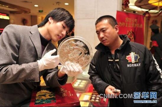 12月21日，工作人員向顧客介紹一款5公斤重的壬辰賀歲紀(jì)念大銀章，其正面的“金龍降喜”圖案，寓意對(duì)龍年萬(wàn)事亨通的美好祝福。