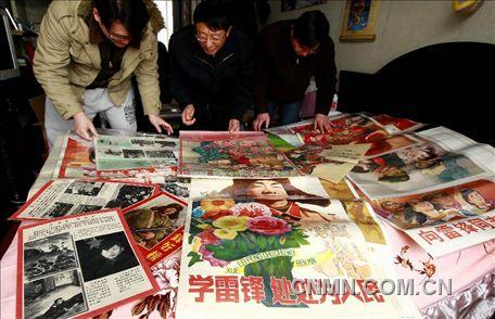 3月1日，房冠龍（中）在家中整理關(guān)于雷鋒的宣傳海報(bào)。