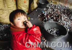 個小朋友在臺州市路橋區(qū)峰江街道一家拆解小作坊內(nèi)玩分揀出來的金屬。